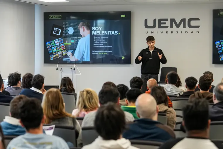 Carlos en el escenario del Press Start con la diapositiva «Soy Melenitas» y el público delante